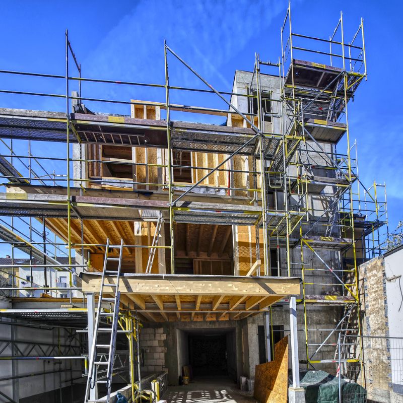 Eingerüsteter Rohbau mit Holzkonstruktion im Obergeschoss